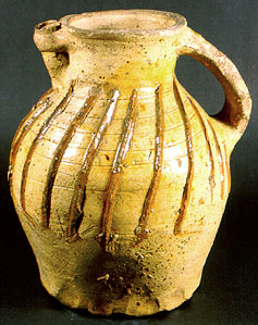 A spouted pitcher with thumbed base used as a decanter at table
